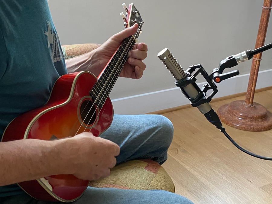 A ukulele being played in front of a Royer ribbon mic in a shock mount